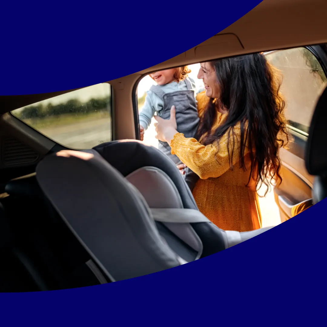 Woman putting child into car seat on purple background